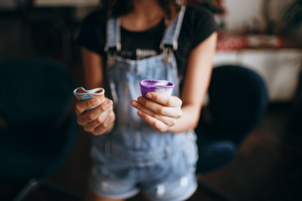 Woman holding colorful menstrual cups in natural indoor light