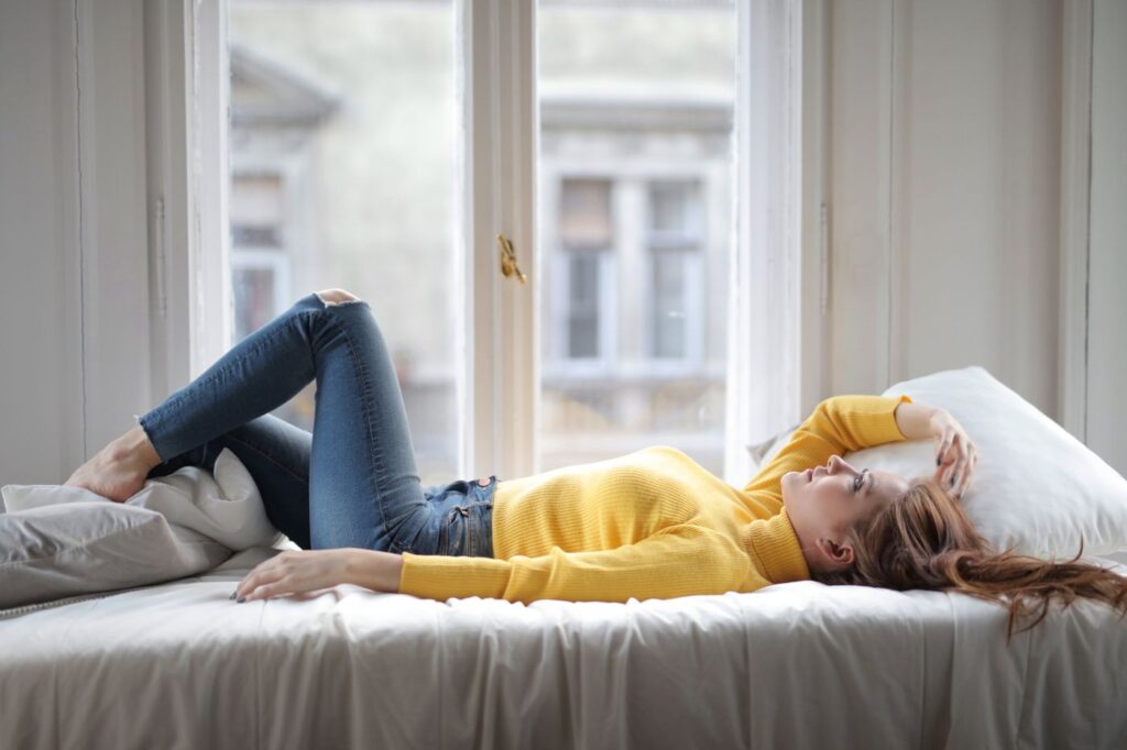 Woman resting by a bright window during a heavier flow day