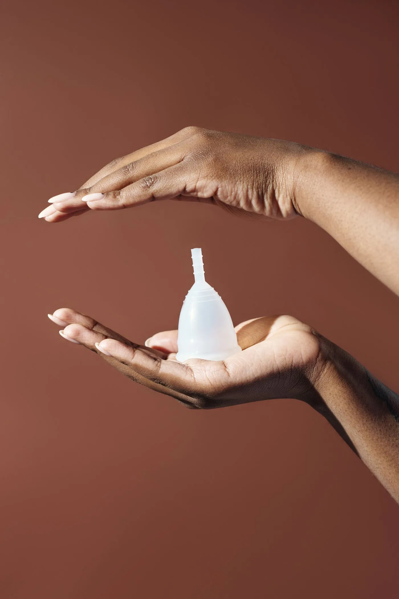 Hands holding a silicone menstrual cup in soft light